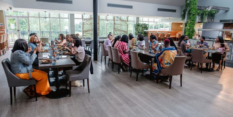 Women in ministry gathered together around tables, laughing and talking over a meal